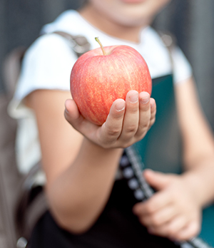 School girl holding out an apple