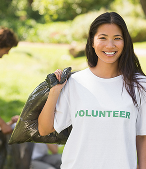 Happy woman in volunteer t-shirt helping with yard work